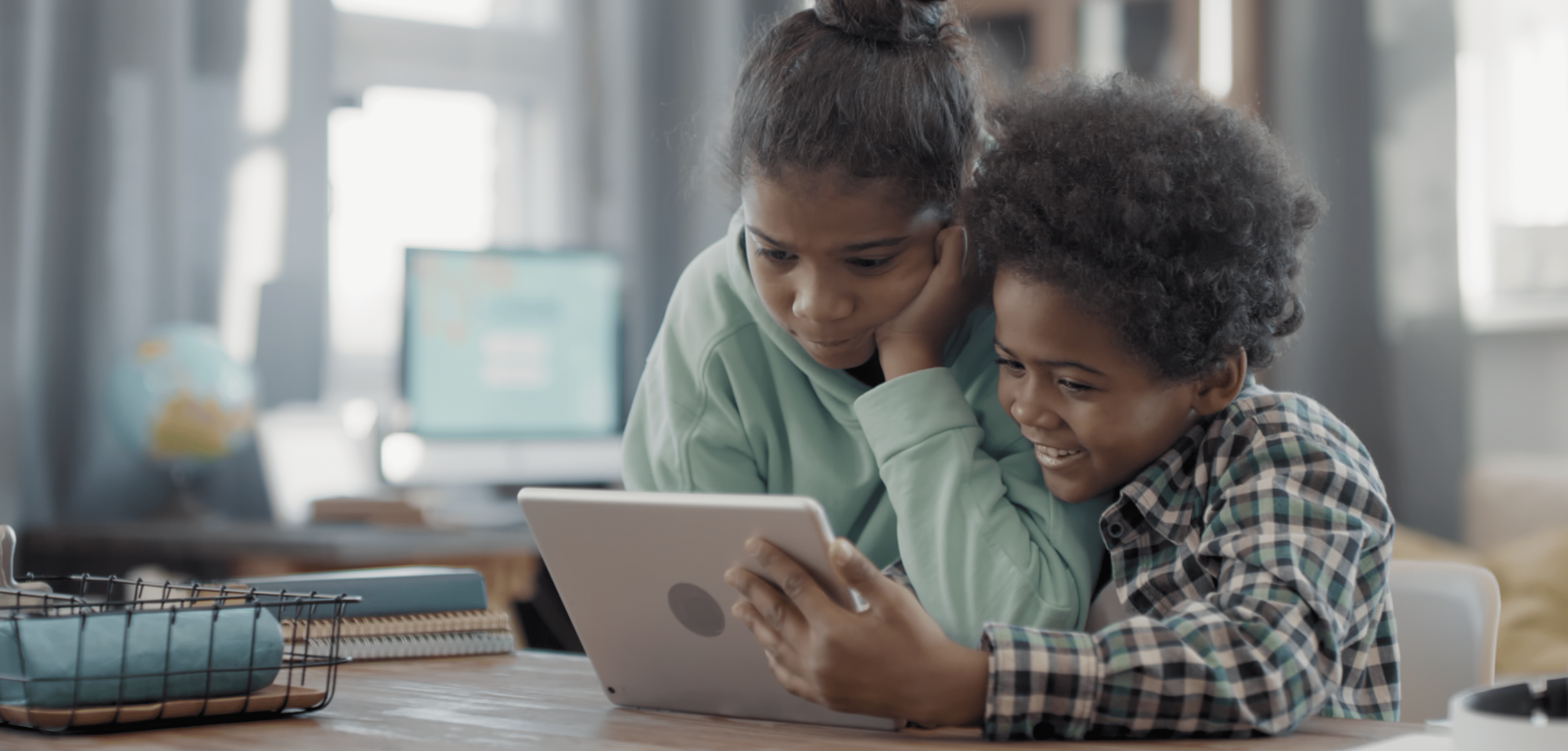 Image of a young boy and a young girl looking at a smart tablet