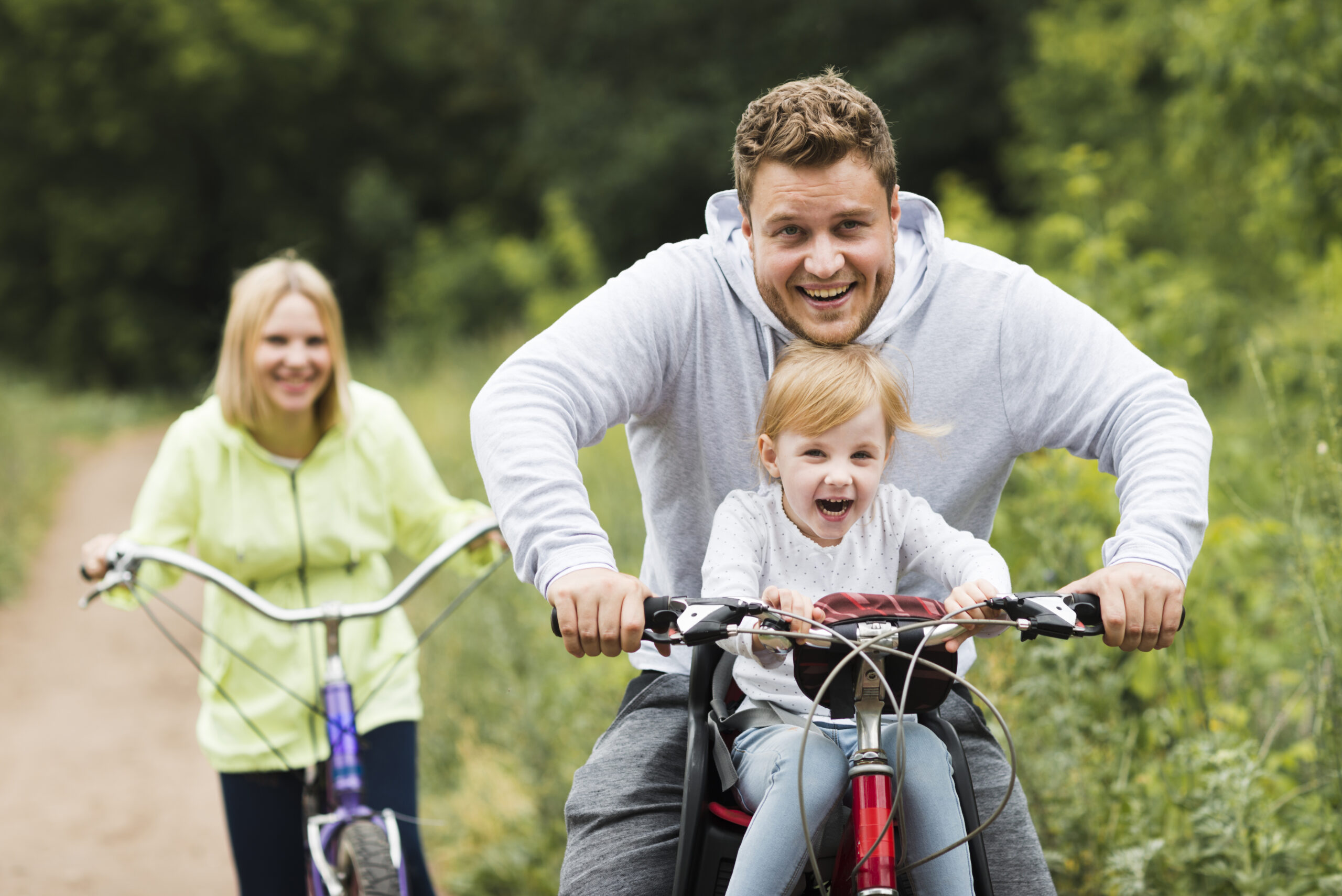 happy-family-with-bikes-forest-road father and mother on a bike ride with child